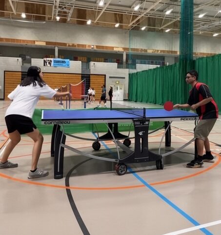A table tennis rally in an indoor sports hall